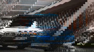 Vista frontal y lateral de un BMW Serie 7 preparado para rally, con barras de luces y portaequipajes.