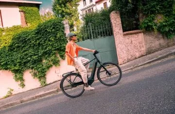 Persona desplazándose en una bicicleta urbana junto a una valla