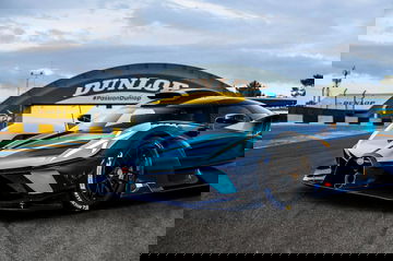 Bugatti azul recortando curva con neumáticos Dunlop, presencia imponente.