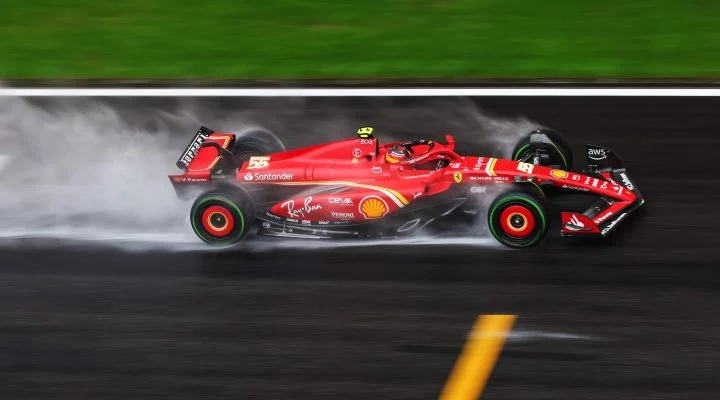 Ferrari rojo en pista mojada, neumáticos Pirelli desplazando agua