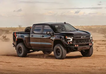 Vista dinámica de un Chevrolet Silverado en acción sobre terreno arenoso.