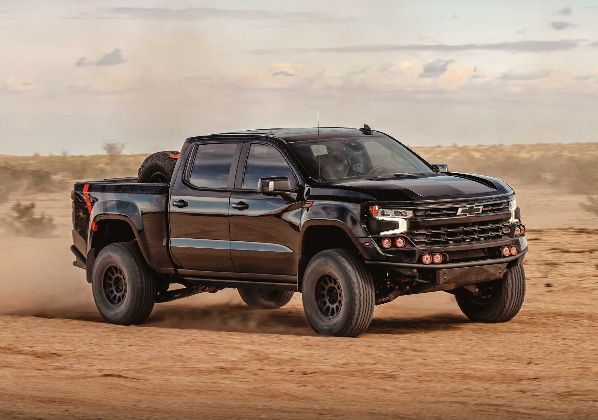 Vista dinámica de un Chevrolet Silverado en acción sobre terreno arenoso.