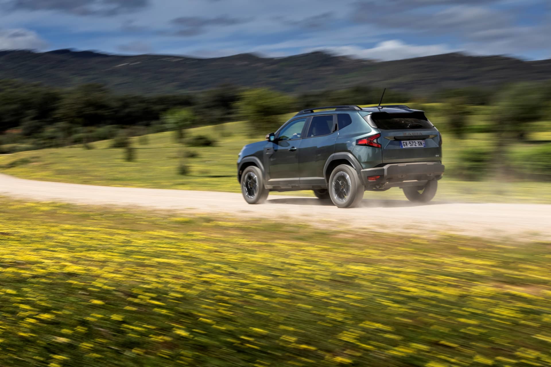 Vista dinámica del Dacia Duster en terreno agreste, destacando su perfil lateral.