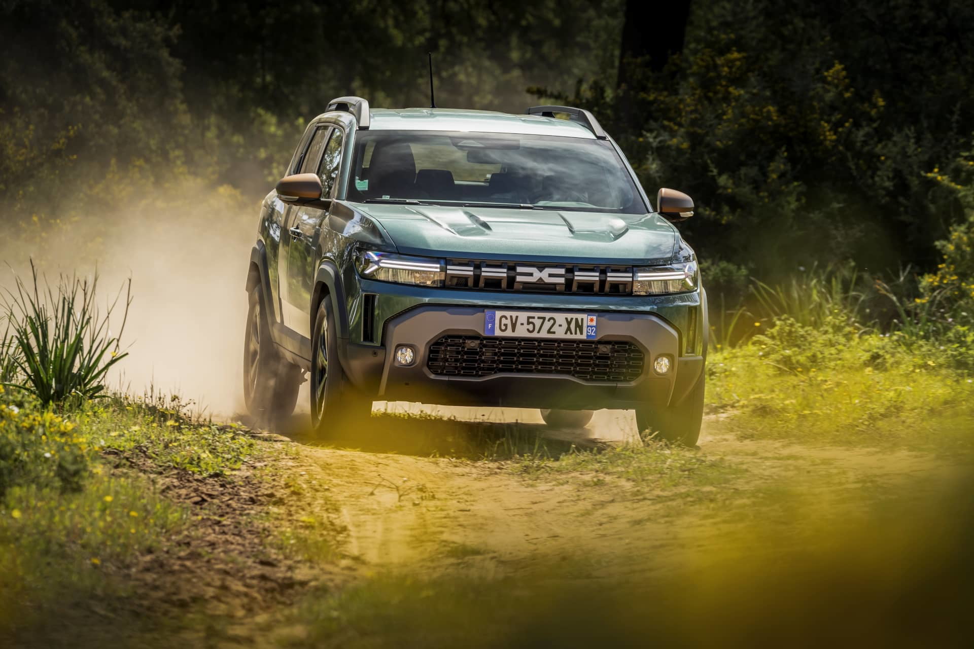 Vista dinámica del Dacia Duster circulando por terreno irregular, destacando su capacidad off-road.