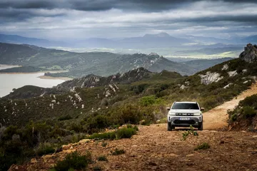Vista lateral del Dacia Duster en un camino de montaña, realzando su capacidad off-road.