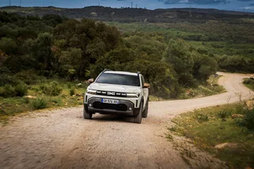 Vista del Dacia Duster tomando una curva en un camino de tierra. Robustez en cada detalle.