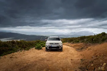 Vista frontal del Dacia Duster en un camino de tierra, destacando su capacidad todoterreno.