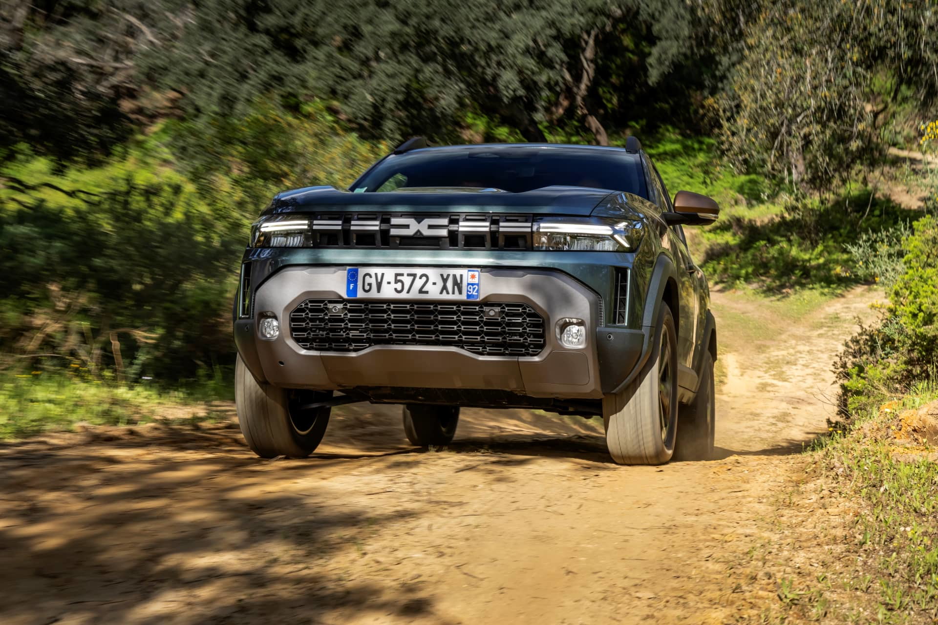 Vista frontal y lateral del Dacia Duster en un camino de tierra, demostrando sus capacidades off-road.