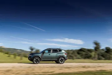 Vista lateral del Dacia Duster en un entorno natural, destacando su perfil robusto y aventurero.
