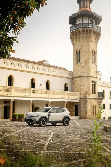 Vista lateral de un Dacia Duster aparcado frente a un castillo histórico