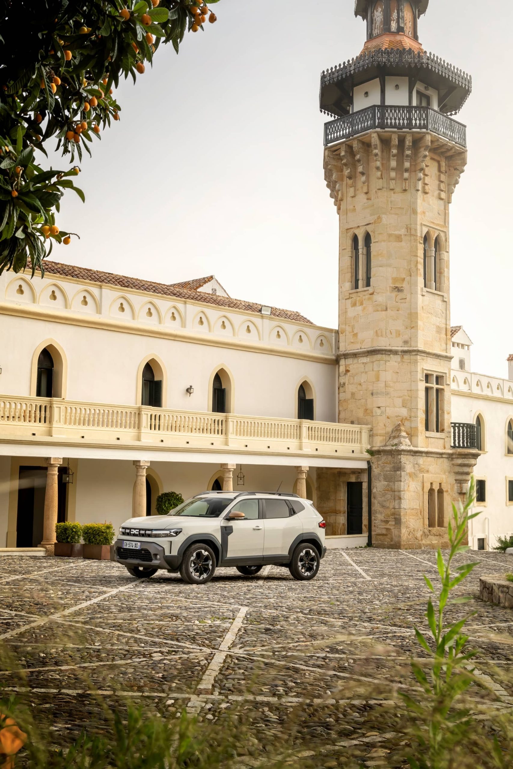 Vista lateral de un Dacia Duster aparcado frente a un castillo histórico