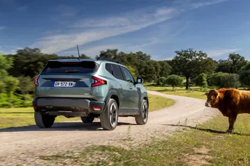 Vista trasera lateral del Dacia Duster en un entorno rural, destacando su capacidad todoterreno.