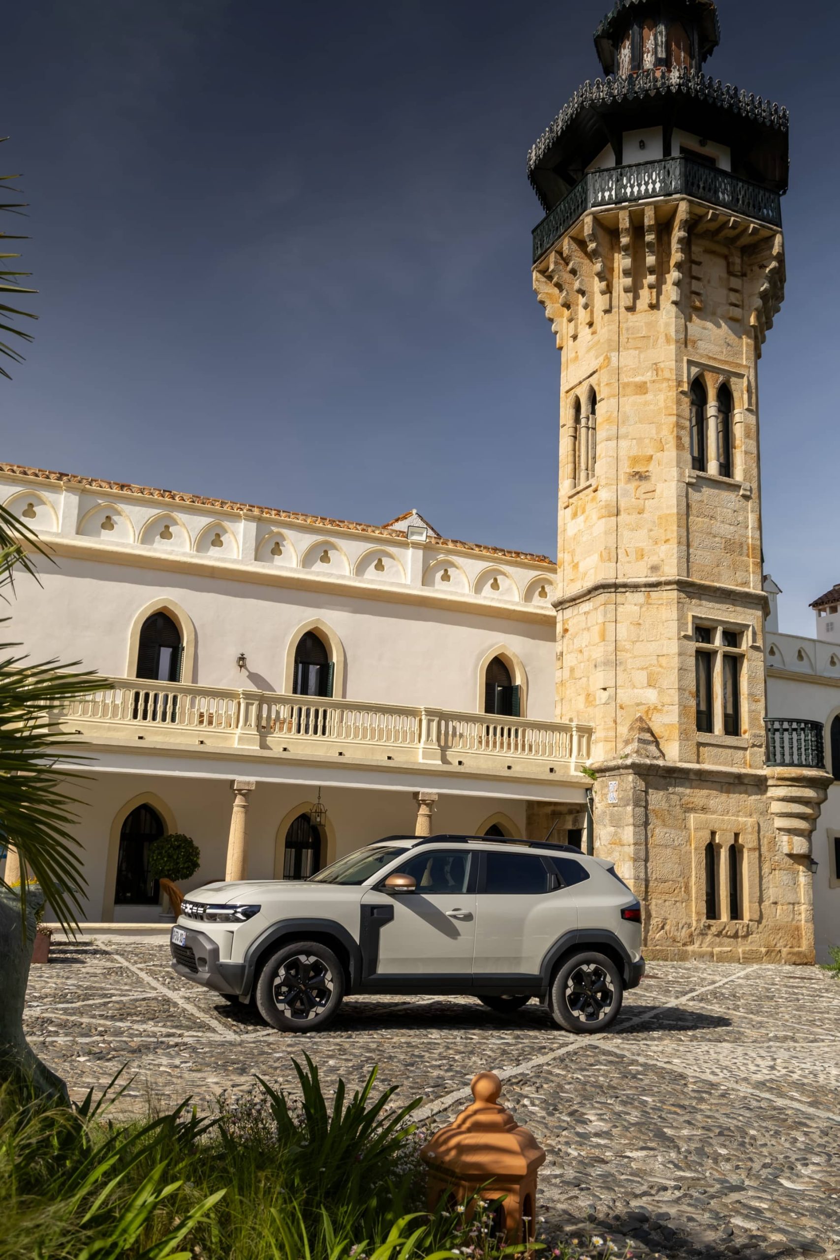 Vista lateral del Dacia Duster aparcado junto a una torre histórica.
