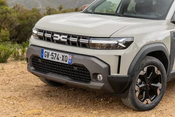 Vista angulada del Dacia Duster destacando su robusta parrilla y línea lateral.