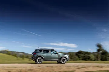 Dacia Duster captado en movimiento, destacando su perfil lateral y diseño robusto.