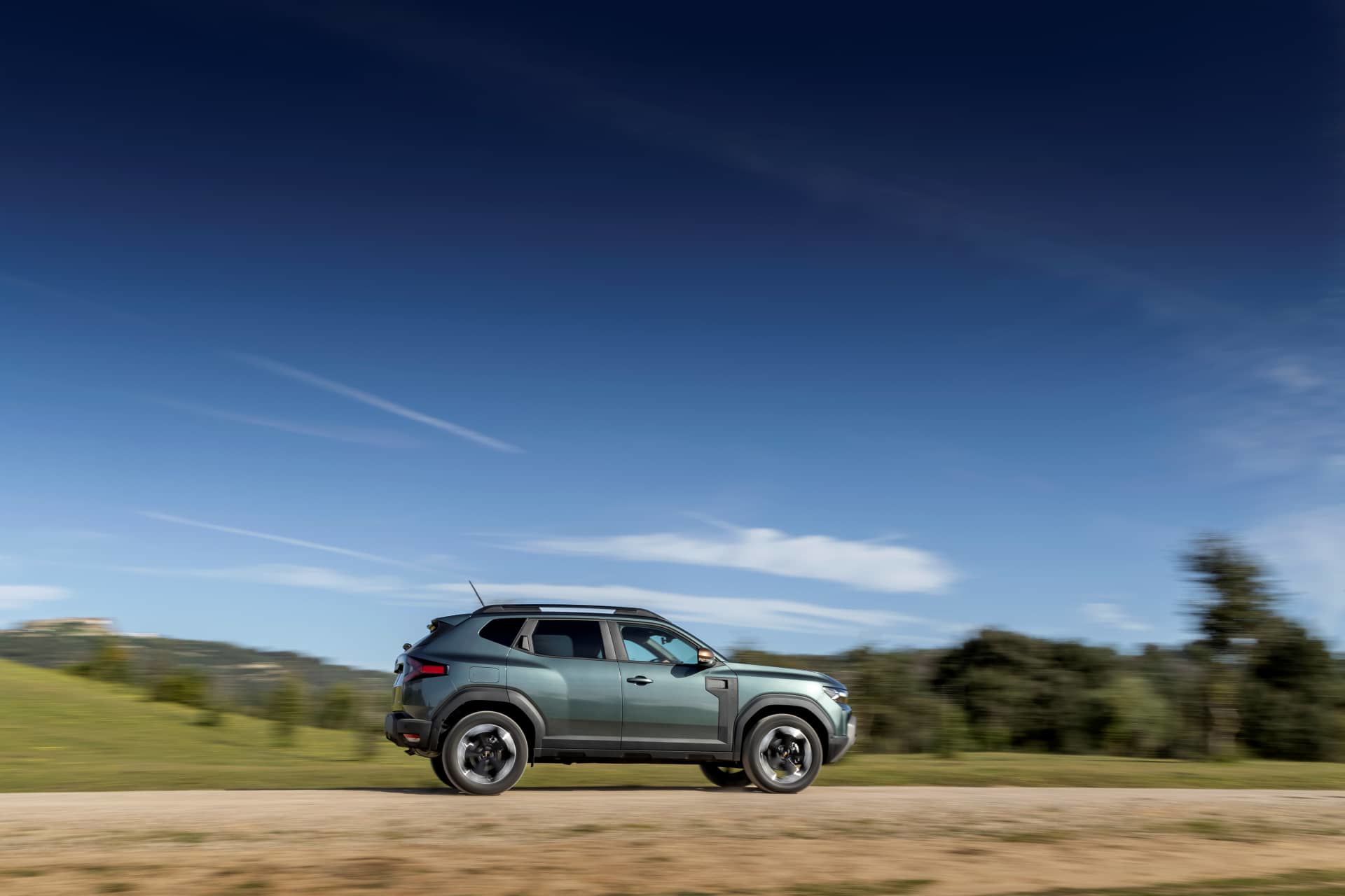 Dacia Duster captado en movimiento, destacando su perfil lateral y diseño robusto.