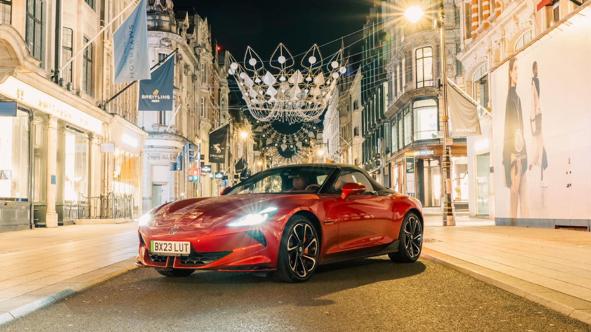 Imagen nocturna de un deportivo de lujo rojo en un entorno urbano, enfocando su frontal y lateral.