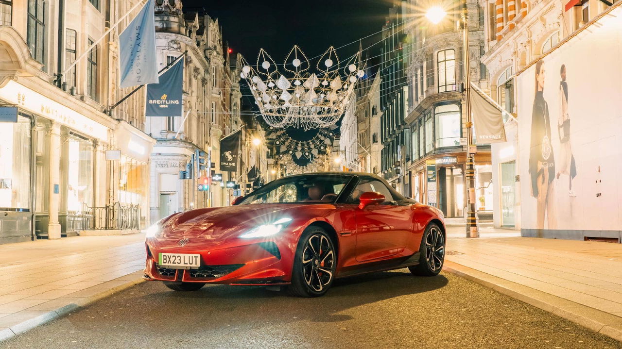 Imagen nocturna de un deportivo de lujo rojo en un entorno urbano, enfocando su frontal y lateral.