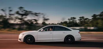 Vista dinámica lateral de un Audi en movimiento, destacando su elegante línea y llantas deportivas.
