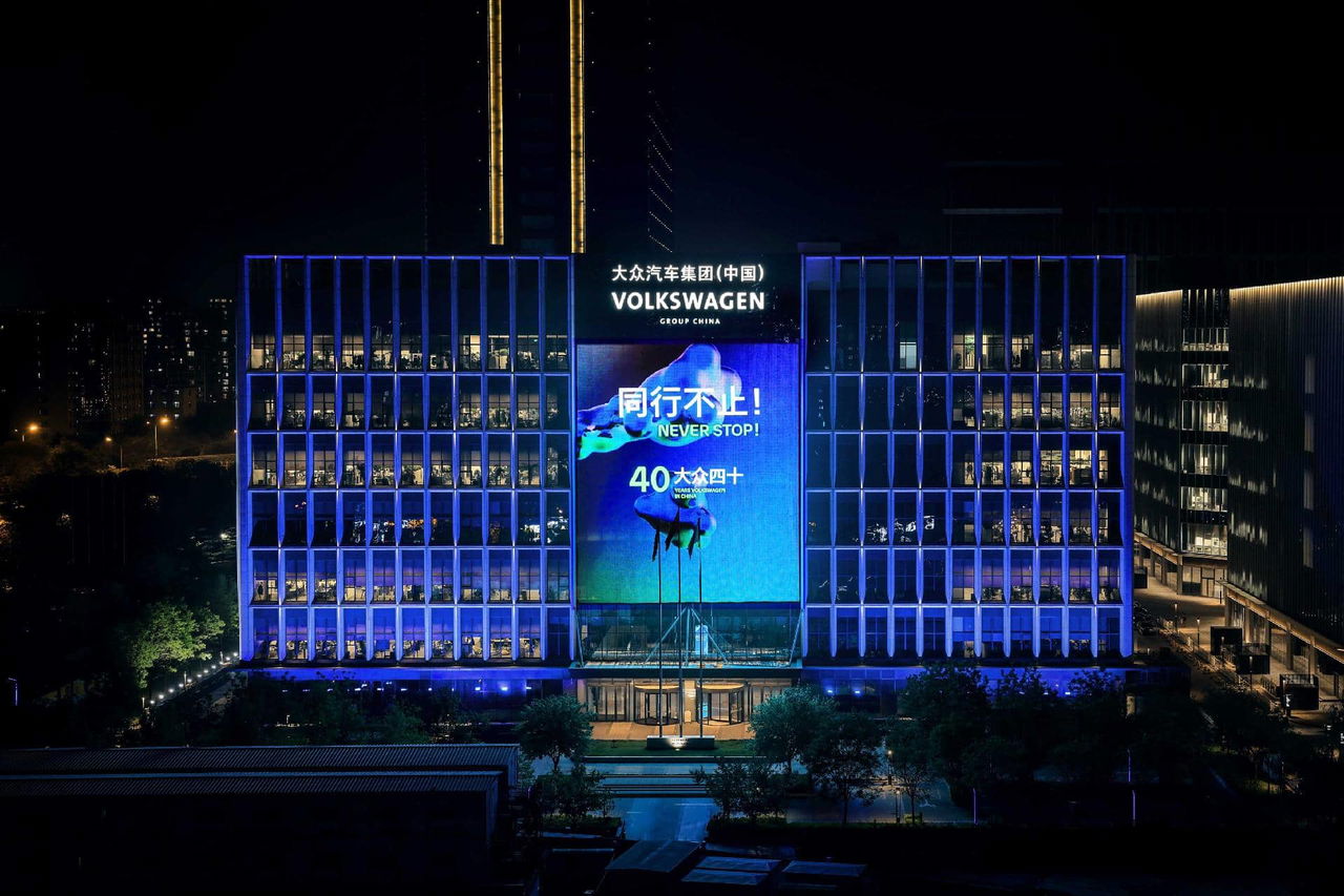 Vista nocturna del edificio de Volkswagen en Beijing, destacando su iluminación y publicidad.