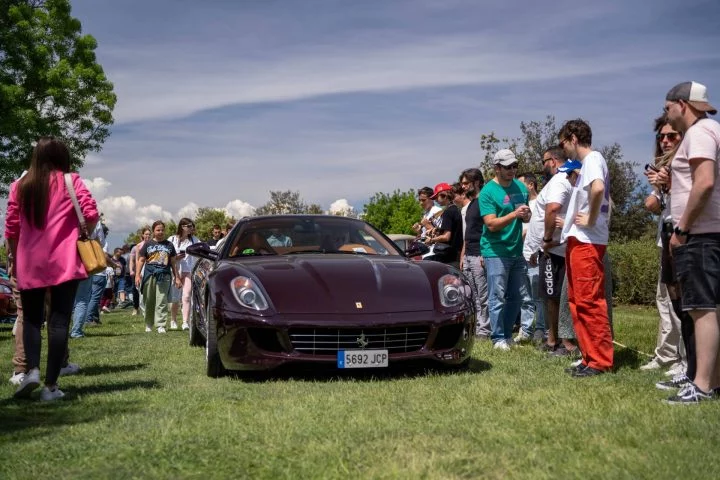 Vista delantera y lateral de un Ferrari en exhibición con espectadores alrededor.