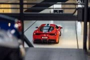 Vista trasera y lateral de un Ferrari rojo en el interior de un garaje iluminado.