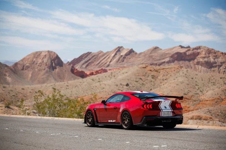 Vista trasera y lateral de un Ford Mustang GT ante un paisaje desértico.