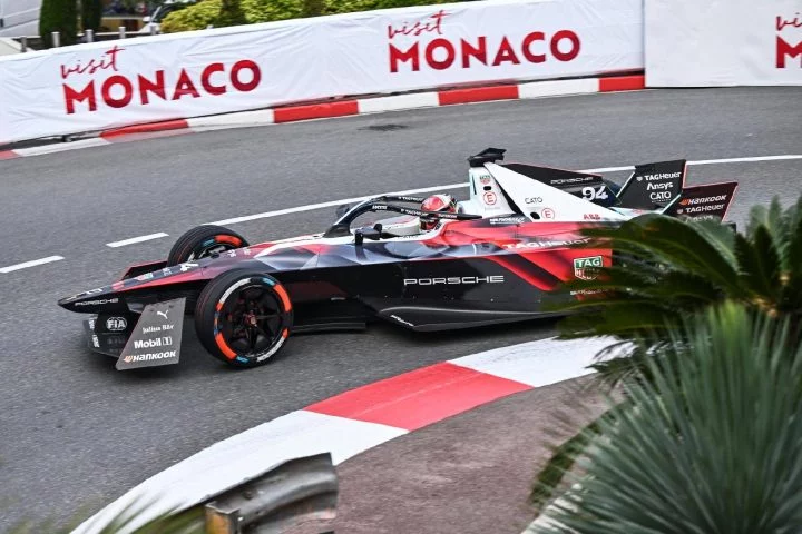Monoplaza Porsche en acción durante el ePrix de Mónaco, curva cerrada con publicidad visible.