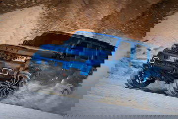 Vehículo todoterreno azul mostrando su capacidad en terreno arenoso.