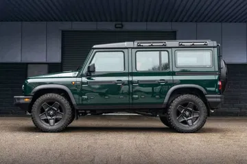 Vista lateral del Ineos Grenadier en un entorno urbano, destacando su diseño robusto y líneas clásicas.