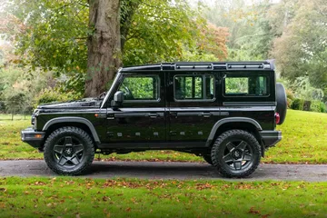 Vista lateral del Ineos Grenadier en entorno natural, resaltando su diseño robusto.