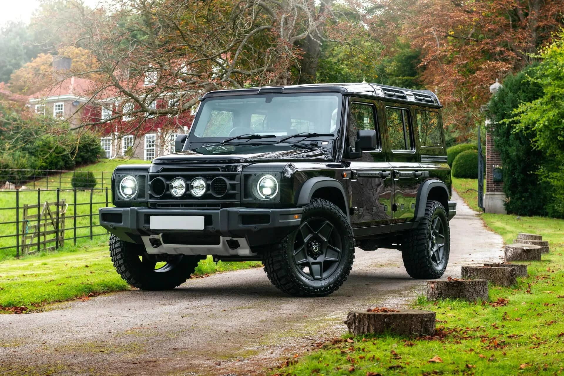 Vista lateral del Ineos Grenadier en un entorno rural, destacando su robustez y diseño clásico.