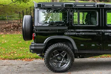 Vista lateral y trasera del Ineos Grenadier en su versión Chelsea 2024, mostrando el diseño robusto y la rueda de repuesto trasera.