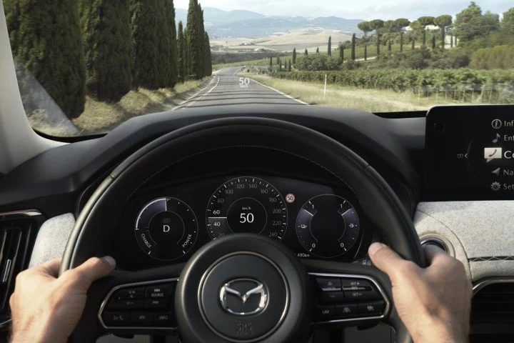 Vista del conductor del Mazda CX-80 2024, enfocando el volante e instrumentación.