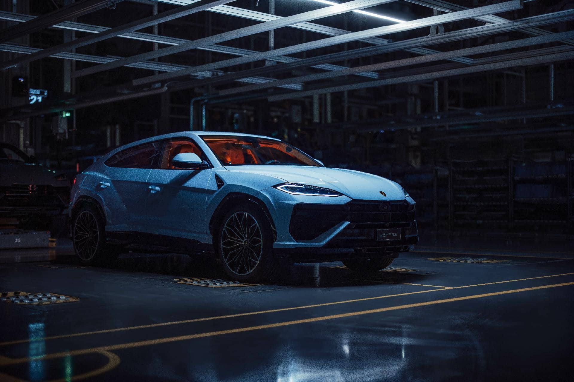 Vista lateral del Lamborghini Urus 2024, iluminado bajo luces artificiales.