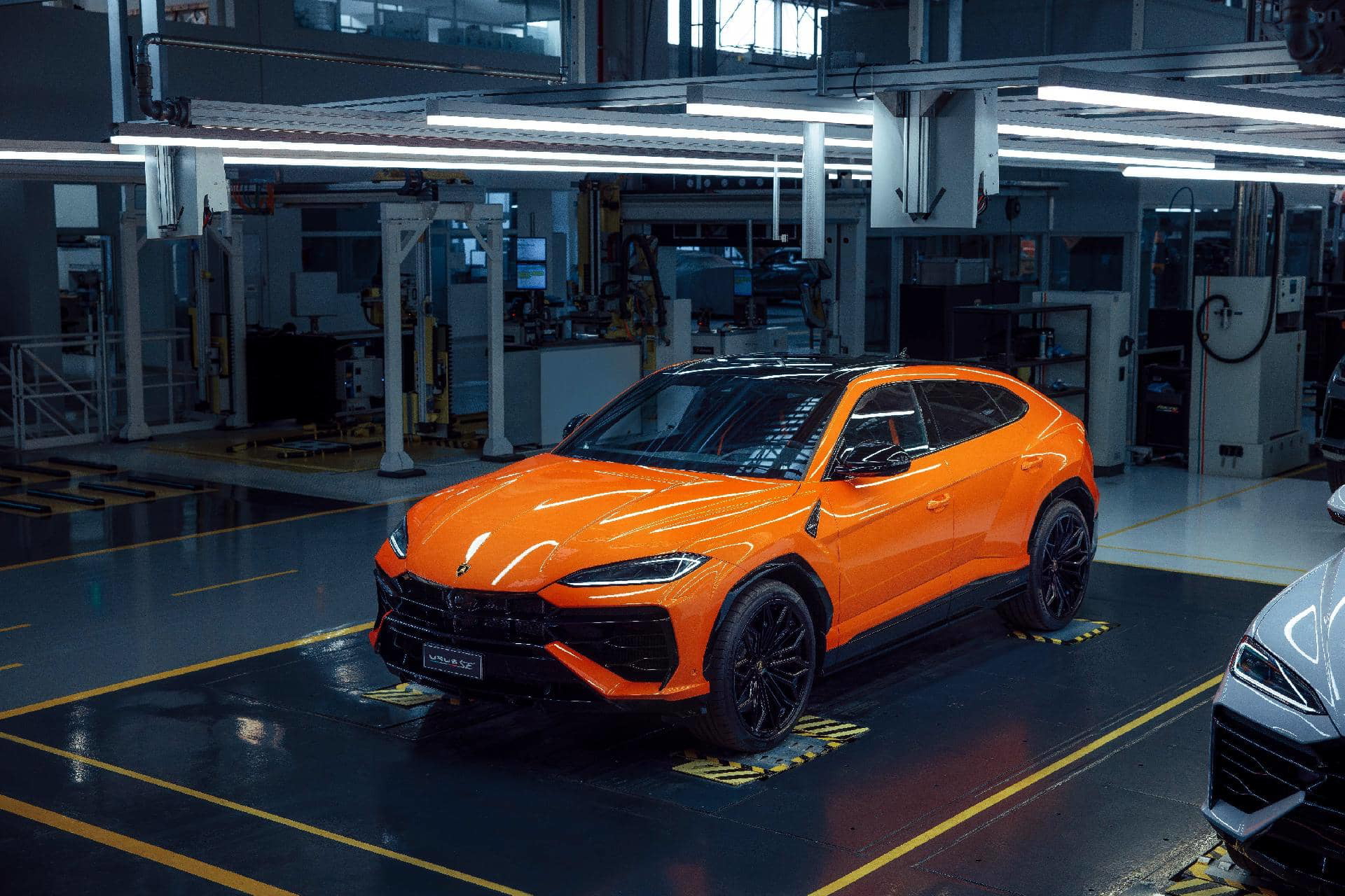 Vista lateral del Lamborghini Urus SE 2024 en la línea de montaje, color naranja vibrante.