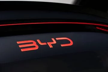 Detalle del logotipo iluminado de BYD en rojo sobre fondo negro, elegante y moderno.