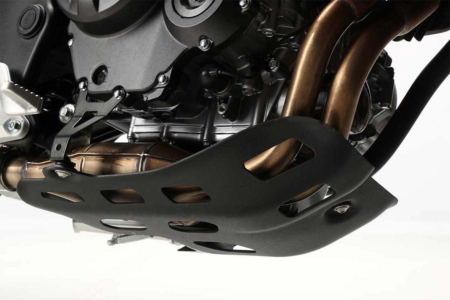Vista cercana del protector de motor y tubos de escape de una moto. Vista cercana del protector de motor y tubos de escape de una moto.