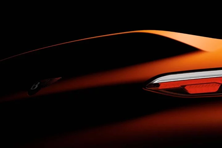 Elegante línea lateral de un Bentley con iluminación dramática que resalta su diseño.