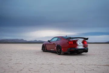 Vista posterior y lateral de un Mustang Shelby GT500 en terreno desértico.