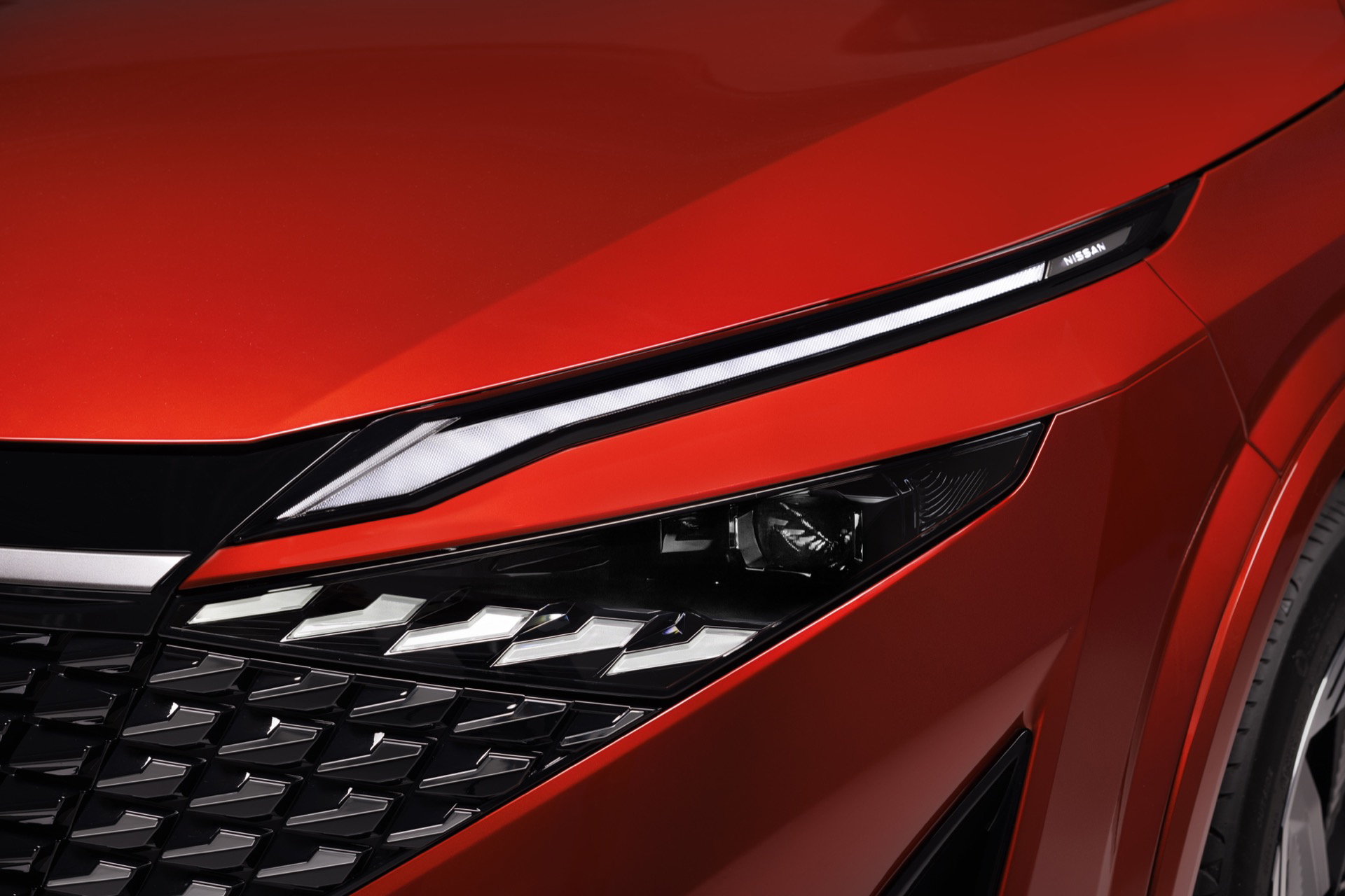 Vista en detalle de la óptica avanzada del Nissan Qashqai 2024, en acabado rojo vibrante.