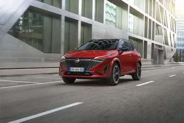 Vista dinámica del Nissan Qashqai 2024 en movimiento, color rojo, destacando su diseño lateral.