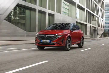 Vista dinámica del Nissan Qashqai 2024 en tono rojo, destacando su diseño frontal y perfil lateral.