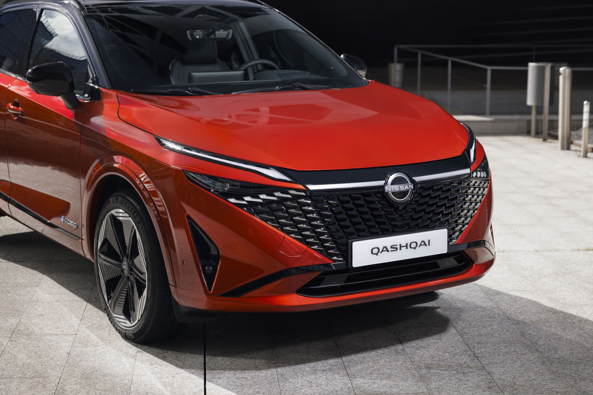 Vista delantera y lateral del Nissan Qashqai 2024 en color rojo, destacando su diseño vanguardista.