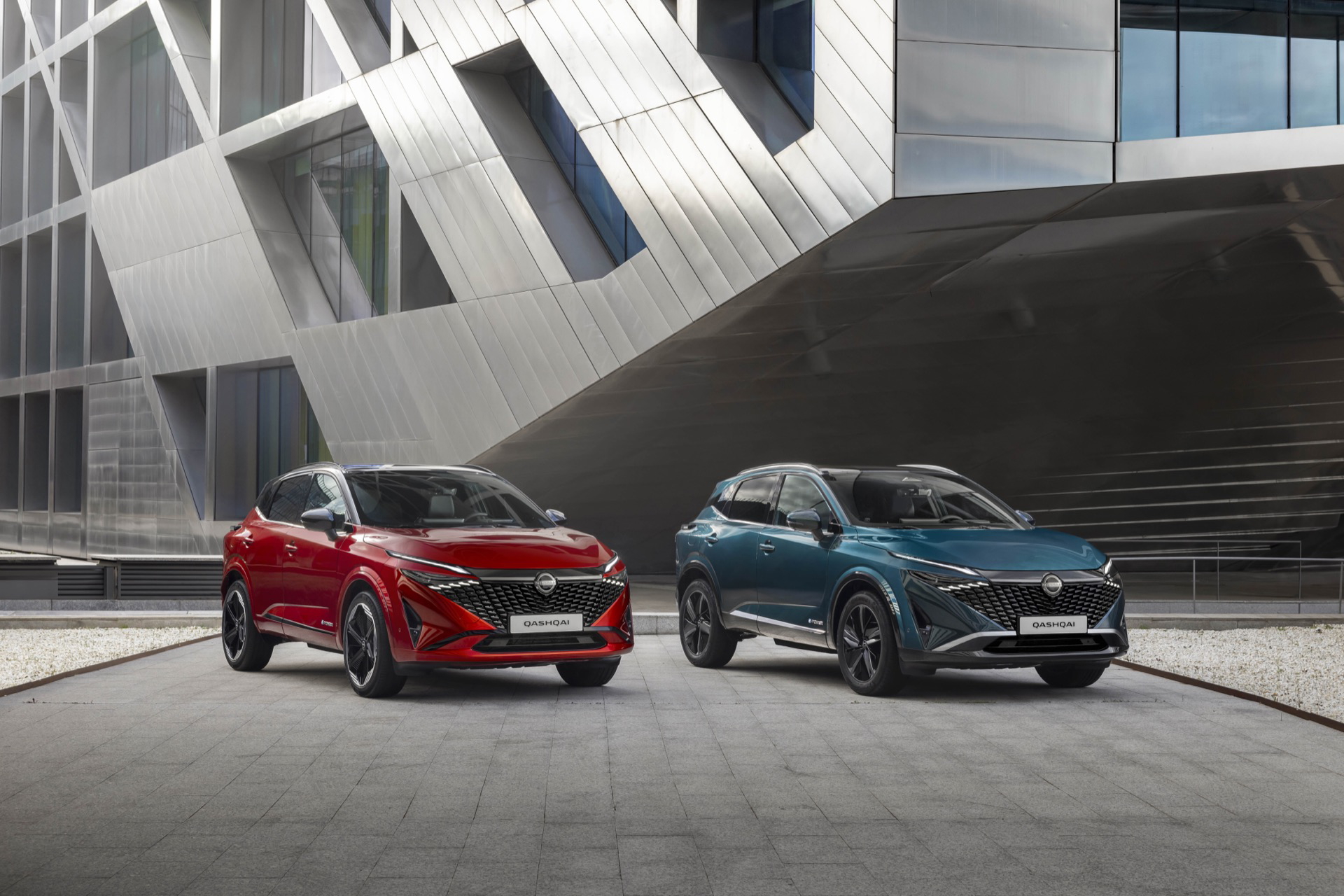 Vista frontal y lateral de dos Nissan Qashqai 2024 en colores rojo y azul.