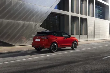 Vista trasera-lateral del Nissan Qashqai 2024 en color rojo, destacando su diseño moderno y líneas dinámicas.