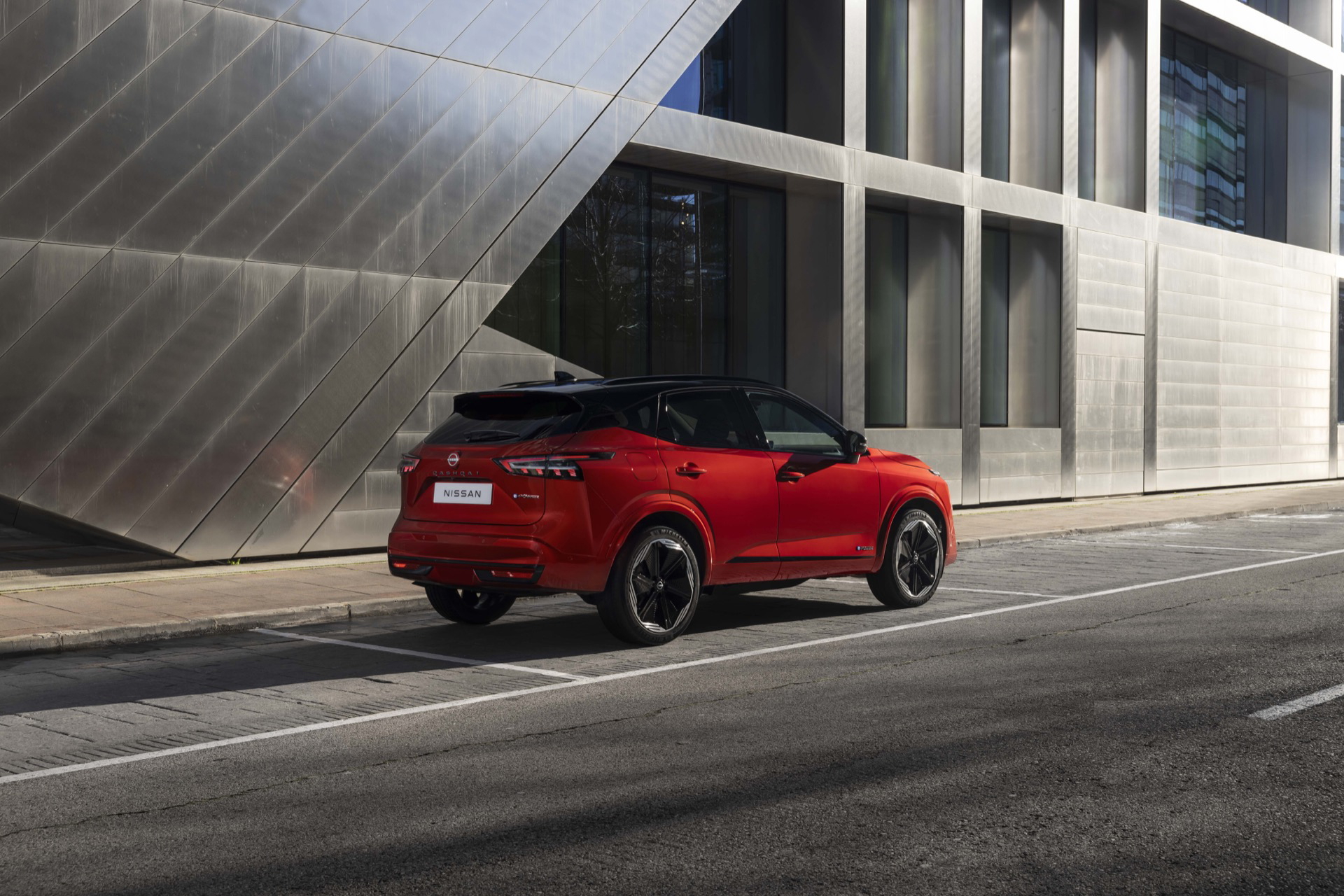 Vista trasera-lateral del Nissan Qashqai 2024 en color rojo, destacando su diseño moderno y líneas dinámicas.
