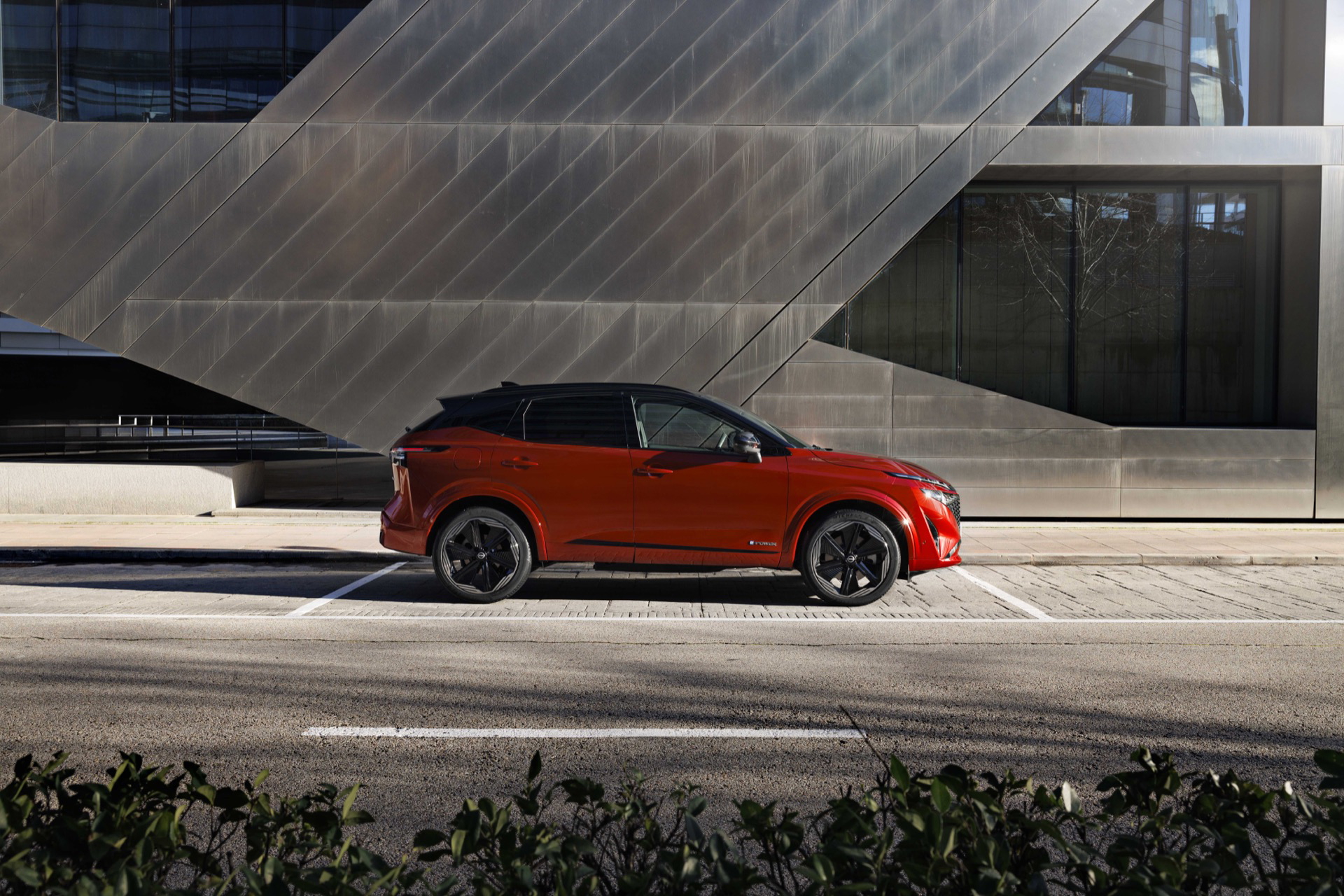 Vista lateral del Nissan Qashqai 2024, mostrando su dinámica silueta en color rojo.