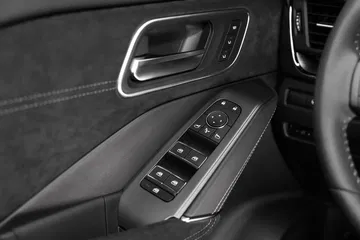 Vista cercana de los mandos de la puerta del Nissan Qashqai 2024, con ajustes de ventanas y espejos.