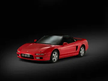 Vista lateral del icónico Honda NSX en rojo, asociado con Ayrton Senna.